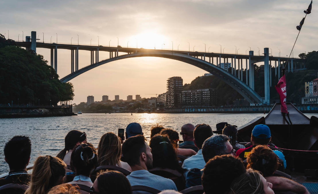 Passageiros num cruzeiro no Douro ao pôr do sol, junto à Ponte da Arrábida, no Porto